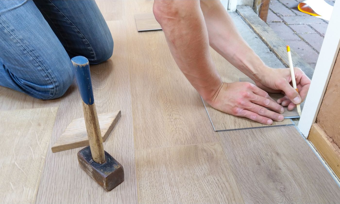 Laminatdielen werden in einem leeren Wohnraum verlegt